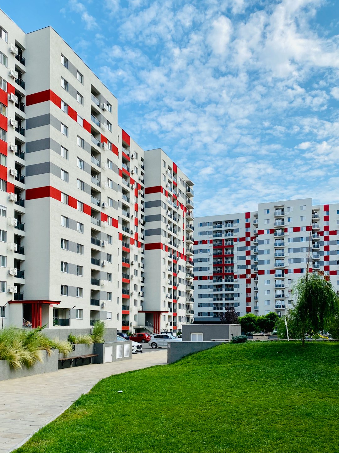 Modern apartment buildings with red and grey panels and balconies.